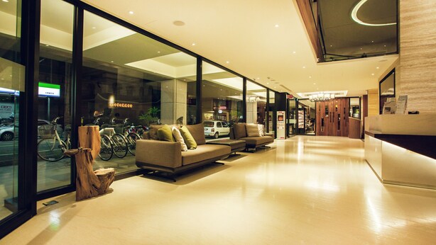 Eine moderne Lobby mit einer Glaswand, einer Sitzecke inklusive Sofas und einem Holzakzent.