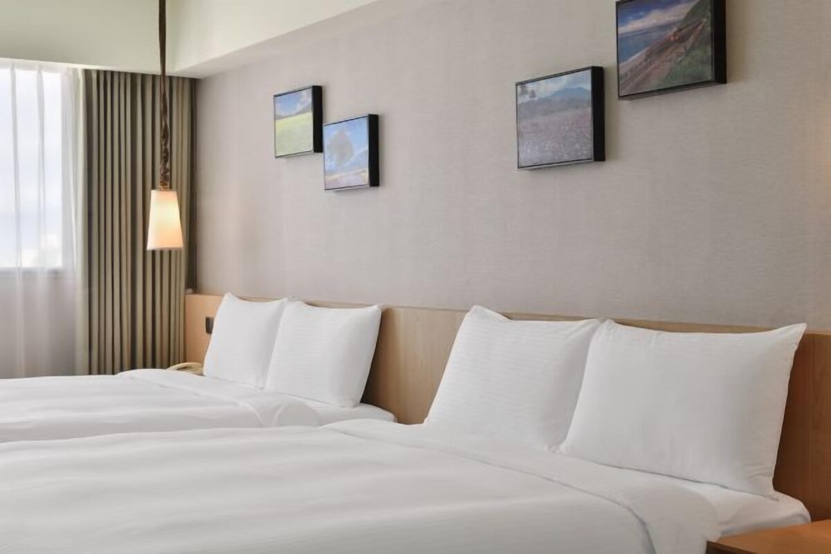 A hotel room with a large bed, a bedside lamp, and three framed pictures on the wall.