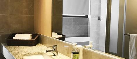 A modern bathroom with a large mirror, two sinks, and a shower area.