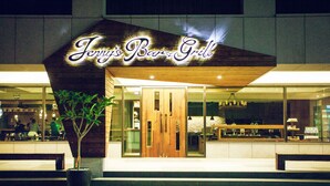 Ein Restaurant mit Holzfassade und einem Neonzeichen, auf dem 'Jerry's Bar & Grill' steht.
