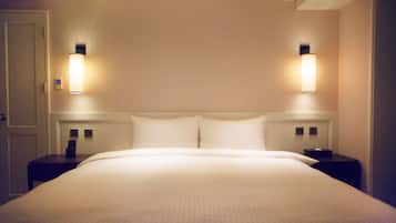 A hotel room with a large bed, two bedside tables, and wall-mounted lamps.