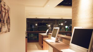 Ein moderner Arbeitsraum mit zwei Computern auf Schreibtischen aus Holz und einem großen Fenster mit Blick auf die beleuchtete Stadt.