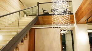 Ein modernes Interieur mit Treppe, einer Hängelampe und einer Couch mit Kissen.