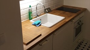 A kitchen with a white sink, wooden countertop, and white cabinets with glass doors. - Alte Post Greifenstein (Sankt Andrae-Woerdern)