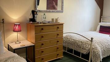 A bedroom with a wooden dresser, a mirror, a bed with a fluffy white cover, a lamp, and a ceiling light.