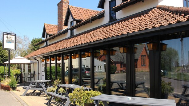 A building with a tiled roof, large windows, and outdoor seating with tables and chairs. - The Crown Lodge Bar Bed & Breakfast  (Lincoln)