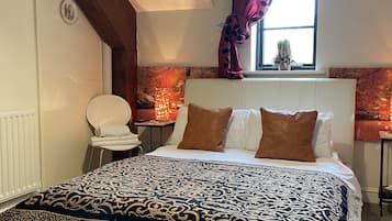 A bedroom with a large bed, a chair, a window with curtains, and a radiator.