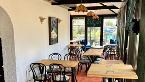 A restaurant interior with wooden tables and chairs, hanging pendant lights, and a view of the outside. - The Crown Lodge Bar Bed & Breakfast  (Lincoln)