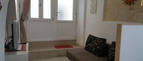 A living room with a sofa, a red rug, and a wall-mounted decorative piece.
