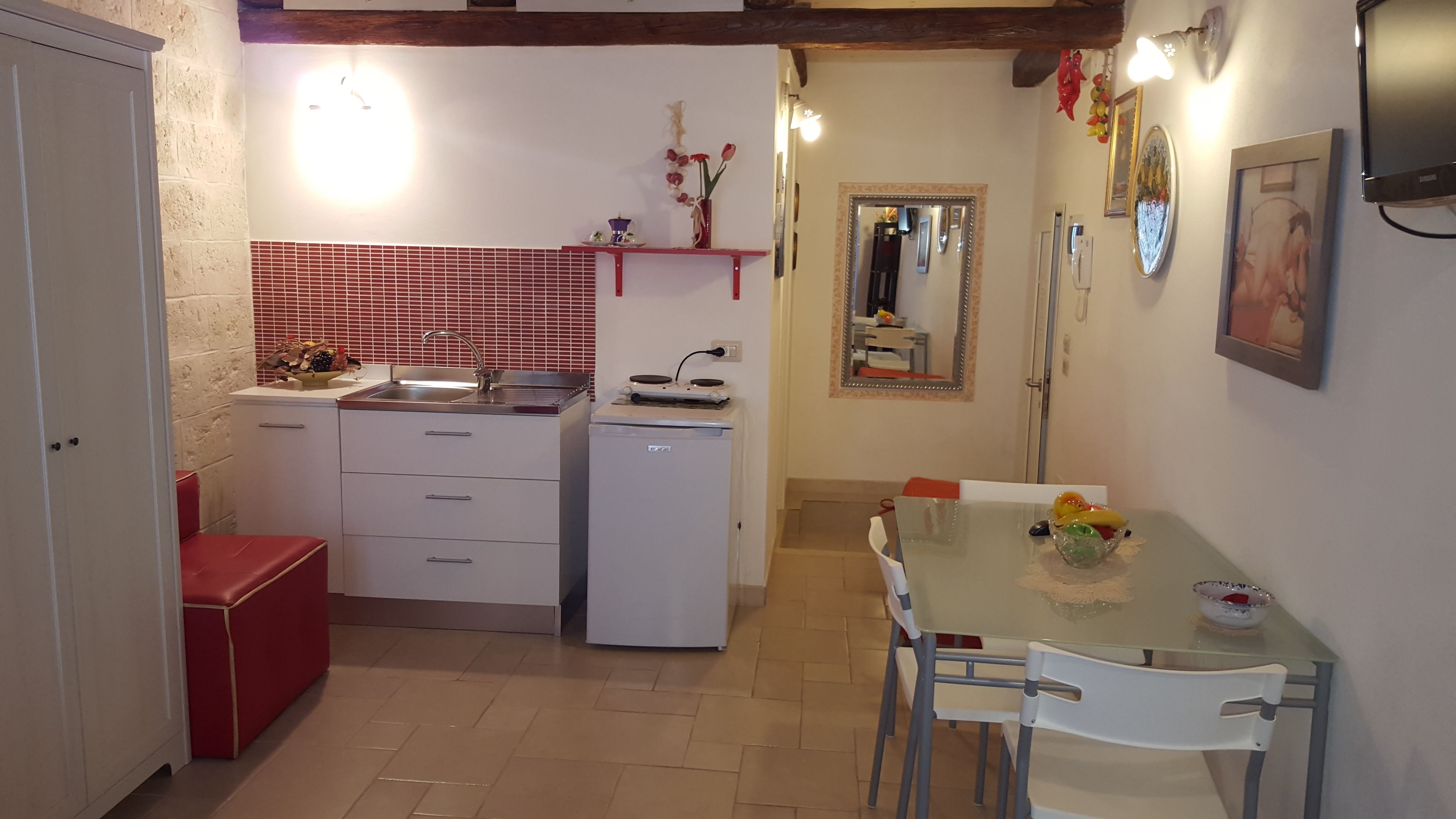 A compact kitchen with a sink, stove, and a dining area with a table and chairs.