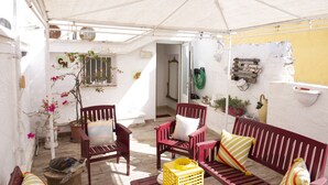 A covered outdoor seating area with wooden furniture and potted plants. - Casa Nave (Monopoli)