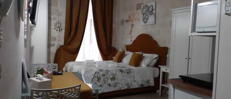 A hotel room with a bed, a desk, a chair, a television, and a window with curtains.