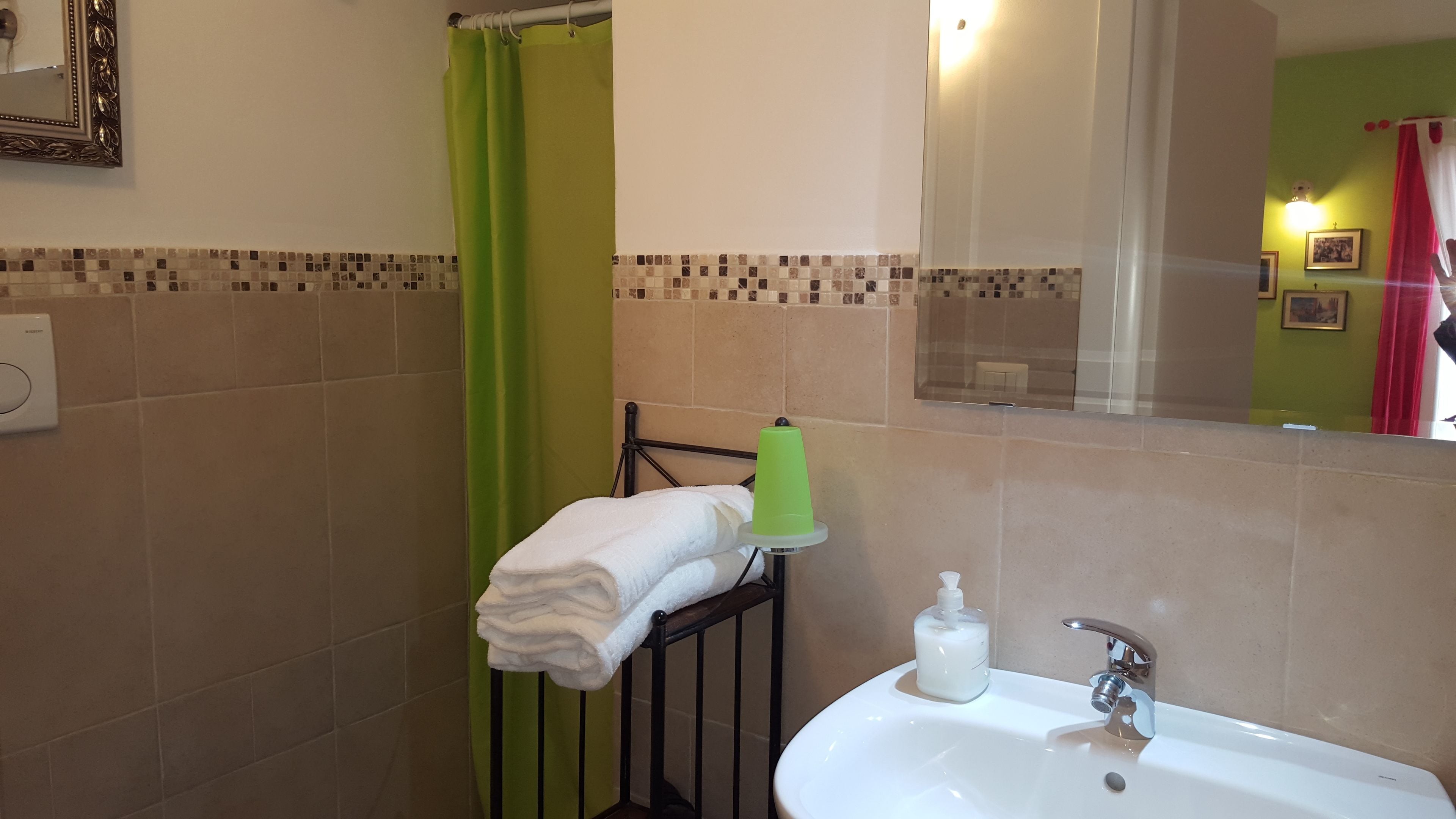 A bathroom with a sink, a green shower curtain, and a towel rack.