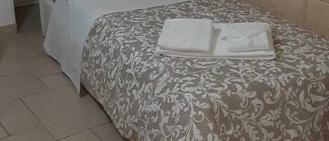 A bedroom with a bed, a nightstand, and a wall-mounted shelf.