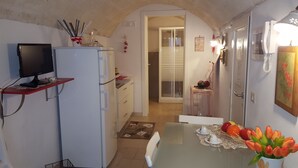 A compact kitchen with a refrigerator, a microwave, and a small dining table with a vase of tulips. - Casa Nave (Monopoli)