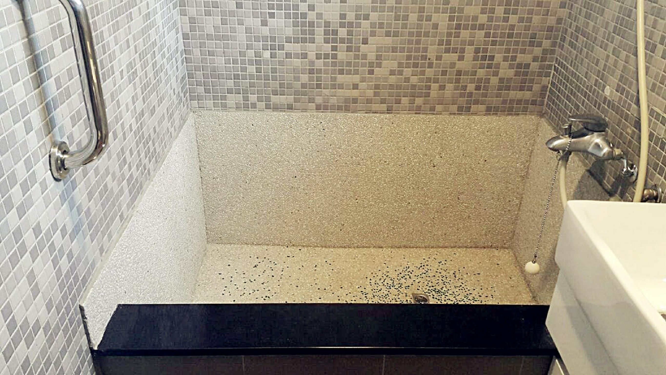 A modern bathroom with a tiled shower area, a black vanity, and a white bathtub.