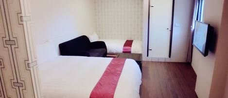 Una habitación de hotel con una cama grande, una cama más pequeña, un televisor y una puerta que da a otra habitación.