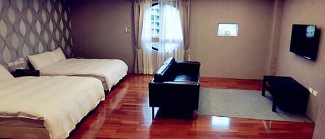 Una habitación de hotel con dos camas, un televisor de pantalla plana, una pequeña mesa y un piano.