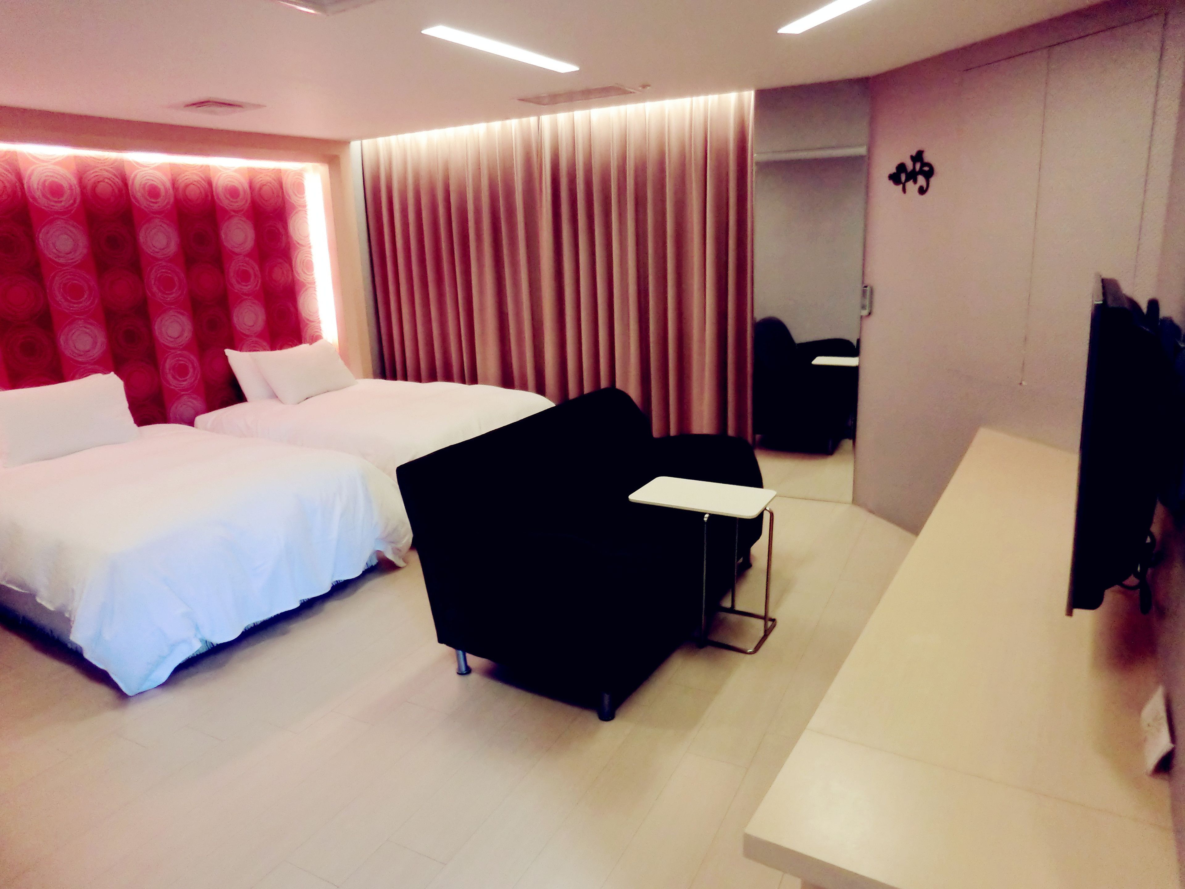 A hotel room with two beds, a desk, a chair, and a mirror.