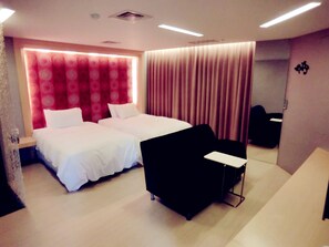 Ein Hotelzimmer mit zwei Betten, einem schwarzen Stuhl, einem Schreibtisch und einem großen Spiegel.