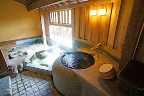 Un onsen japonés tradicional con un manantial de piedra caliente, paredes de madera y suelo de baldosas.