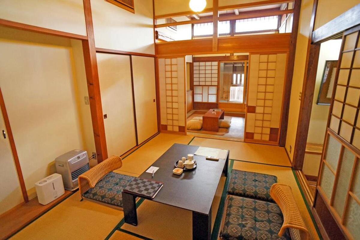 A traditional Japanese room with tatami flooring, a low table with cushions, and sliding doors.