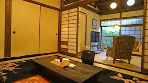 Une pièce de style japonais traditionnel, avec un sol recouvert de tatamis, une petite table basse accompagnée d’un service à thé et une porte coulissante.