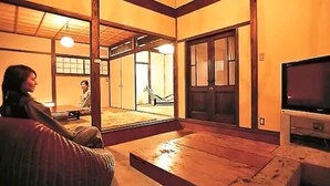 Une pièce de style japonais traditionnel, avec un sol recouvert de tatamis, une table basse et un téléviseur.