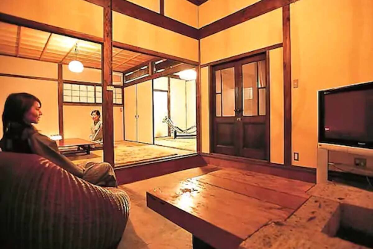 A traditional Japanese-style room with tatami flooring, a low table, and a television.
