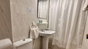 A bathroom with a toilet, sink, and shower curtain. - Hotel El Paraiso (Aguilas)