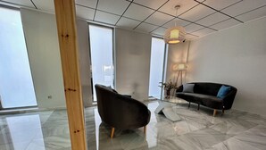 A modern living room with a glass coffee table, a dark sofa, and a wooden accent wall. - Hotel El Paraiso (Aguilas)