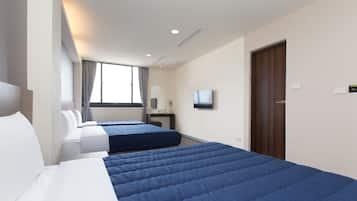 A hotel room with two beds, a TV, a desk, and a window with curtains.