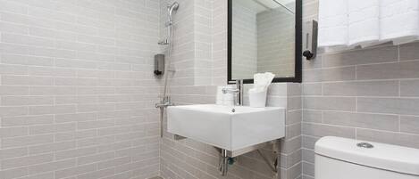 A modern bathroom with a white sink, a glass shower enclosure, and a toilet.