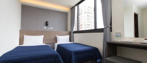 A hotel room with two beds, a desk, a chair, a large window, and a mirror.
