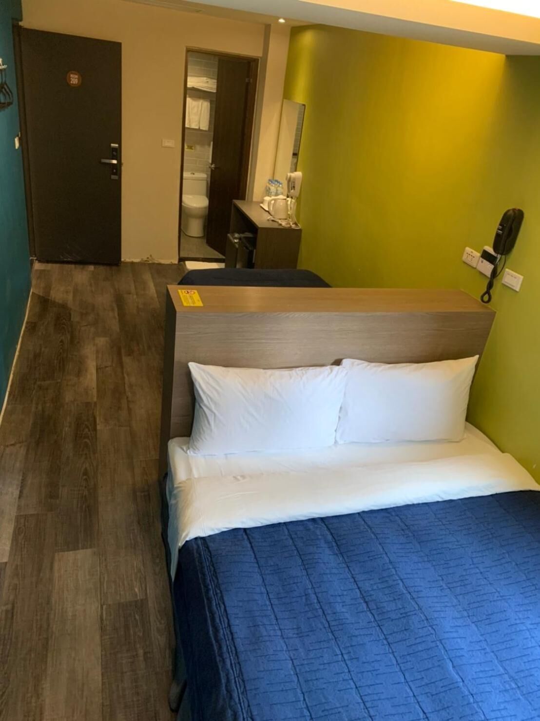 A hotel room with a bed, a desk, a chair, and a bathroom visible through an open door.