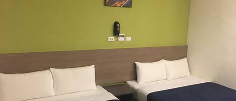 Una habitación de hotel con dos camas, una pared verde y un cuadro sobre las camas.
