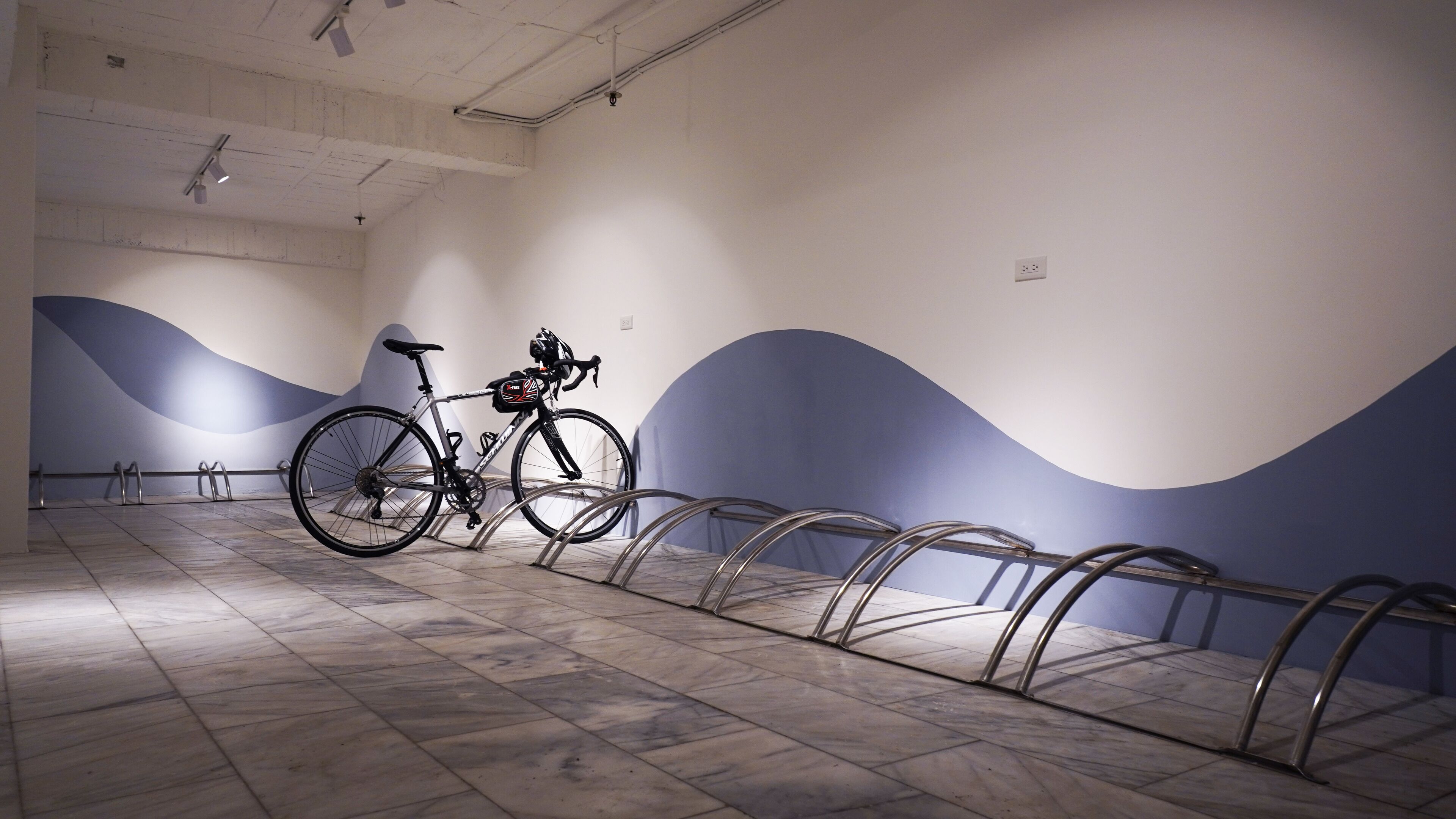 A bicycle parked in a room with a tiled floor and a blue and white wall design.