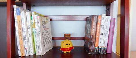 A bookshelf with a variety of books and a small yellow bear figurine.