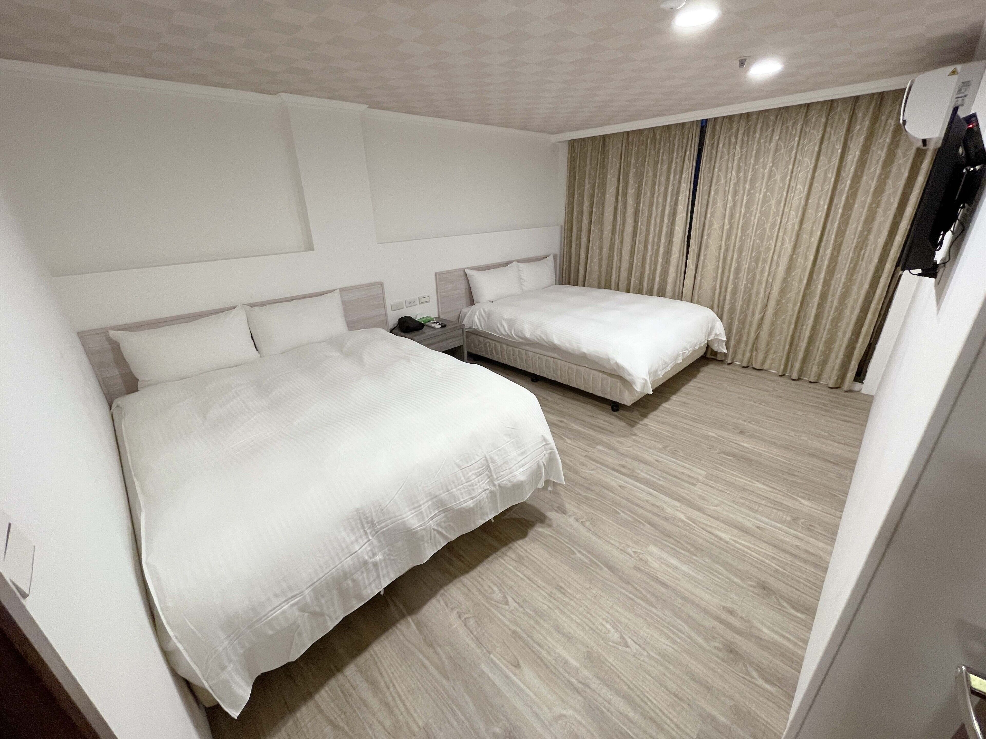 A hotel room with two beds, a flat-screen TV, and a minibar.