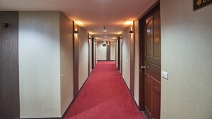 Un pasillo de hotel con alfombra roja, puertas de madera y un letrero que indica la habitación 613.