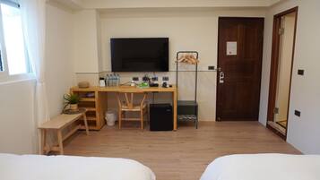A small, tidy room with a wooden desk, a television, a bed, and a door.