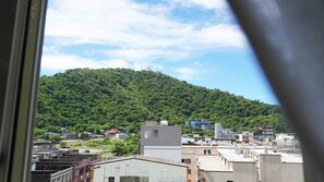 Vista de un paisaje urbano con edificios y una colina cubierta de vegetación.