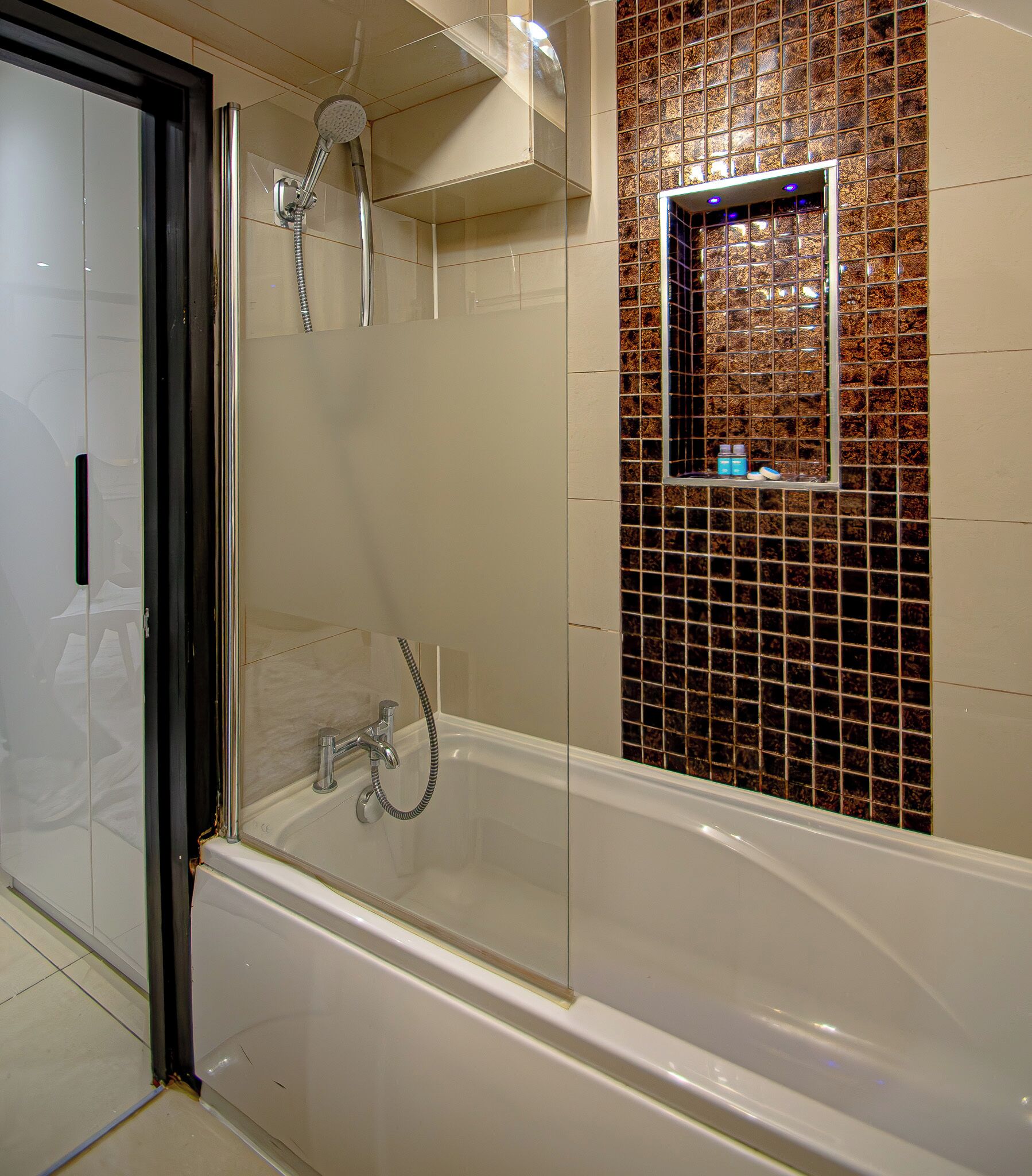 A modern bathroom with a glass-enclosed shower, a bathtub, and a tiled wall with a decorative square window.
