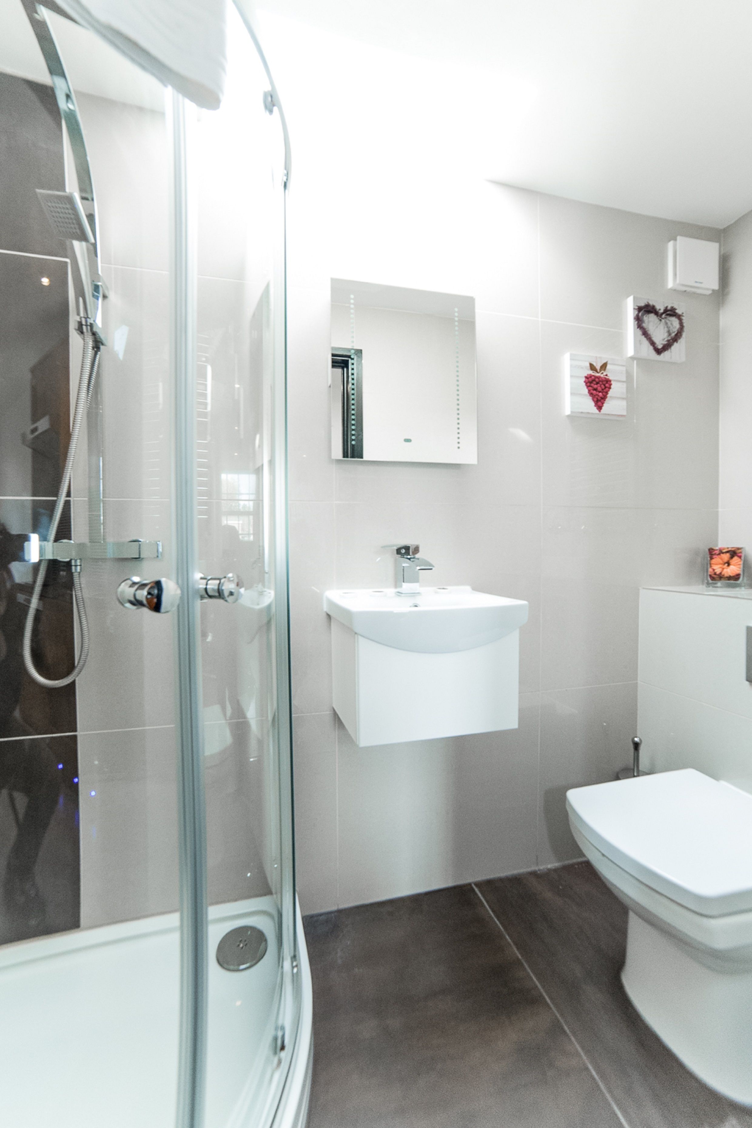 A modern bathroom with a glass-enclosed shower, a white sink, and a toilet.
