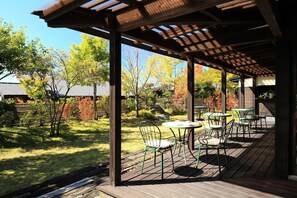 An outdoor patio with wooden flooring, metal chairs, and tables.