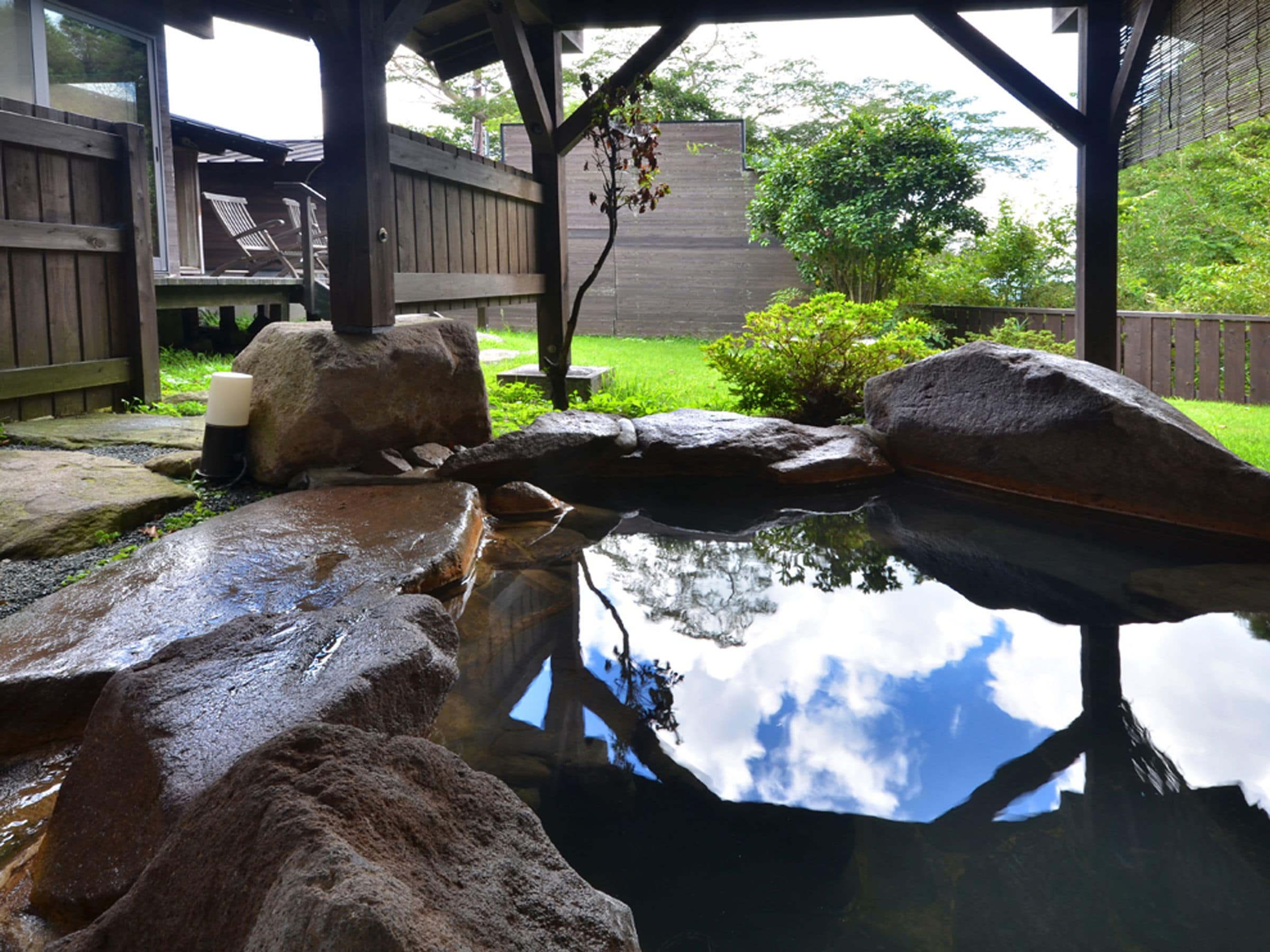 A pond with rocks and a wooden deck with chairs.