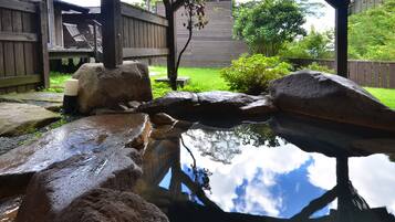 A pond with rocks and a wooden deck with chairs.
