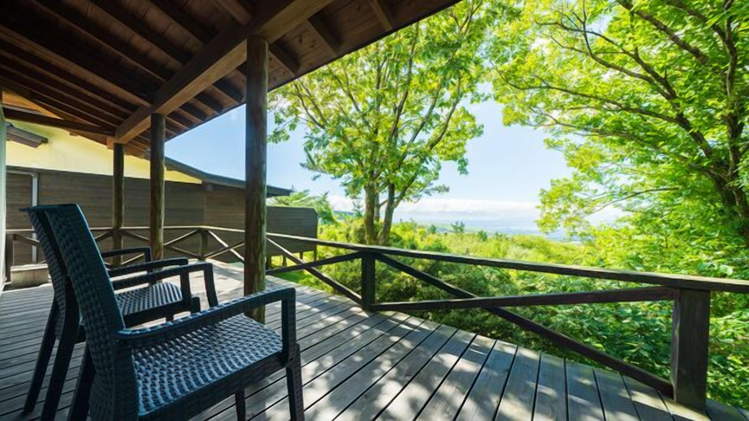 A wooden deck with a bench, overlooking a lush green landscape.
