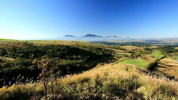 Vista panorámica de un paisaje montañoso con cielo despejado, que muestra colinas ondulantes, un valle y montañas distantes.