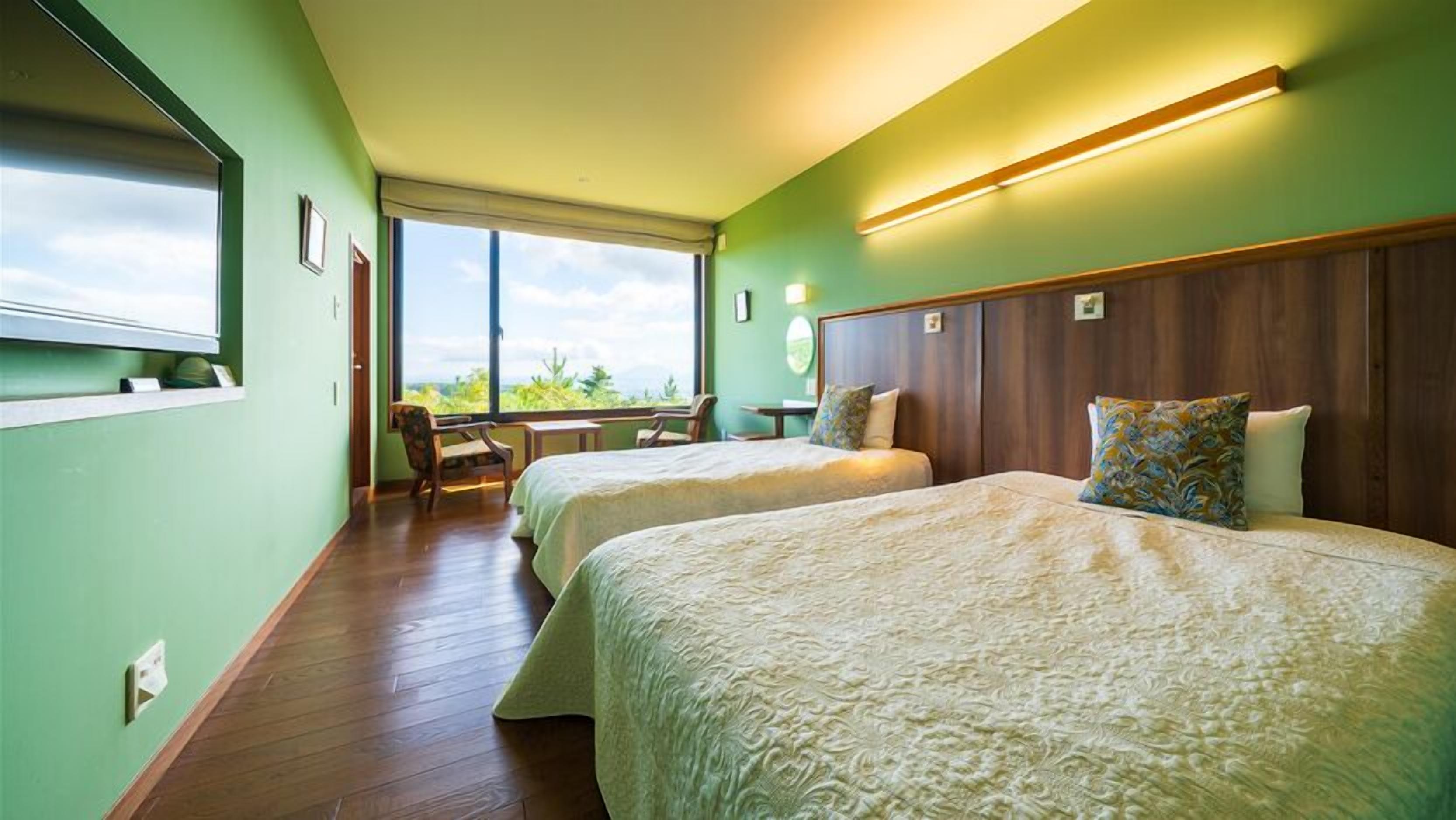 A hotel room with two beds, a desk, a chair, and a large window.
